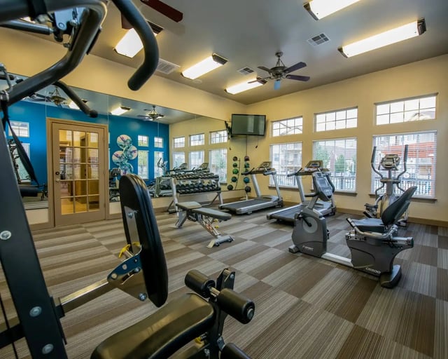 On-site fitness center with treadmills, ellipticals, free weights, and mirrors.