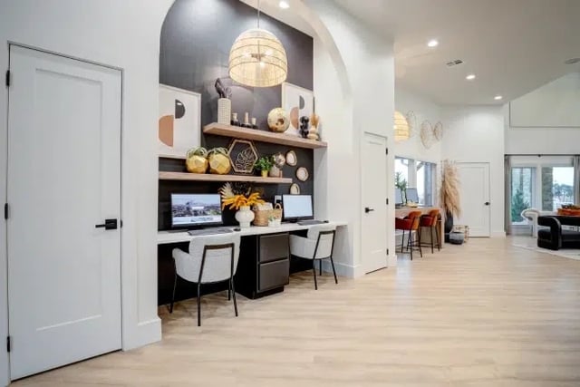 Contemporary apartment community lounge with built-in desks, shelving, and pendant lights