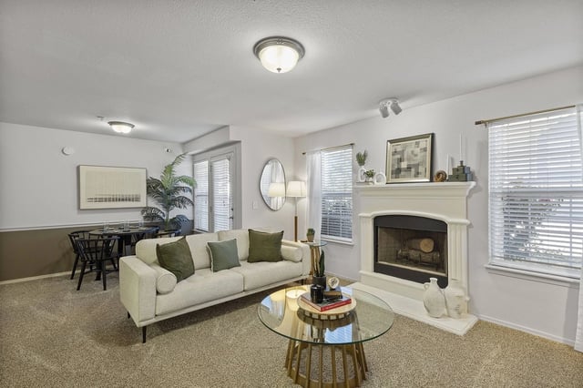 Living room with fireplace, sofa, coffee table, and dining area.