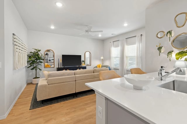 Modern living room and kitchen area with large sectional couch, TV, and island.