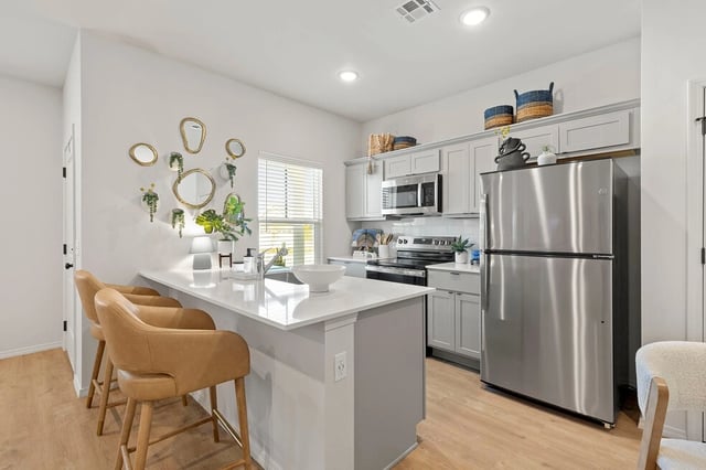 Modern kitchen with stainless steel appliances, white quartz countertops, and light gray cabinetry.