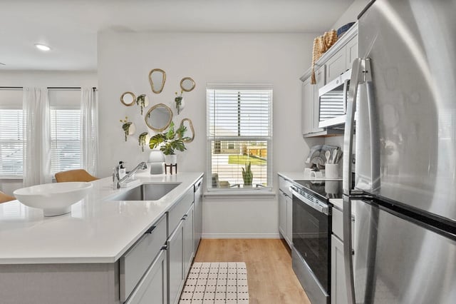 Modern kitchen with stainless steel appliances, gray cabinets, and a large sink.