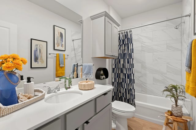 Modern bathroom with a single vanity, toilet, and bathtub with a shower.