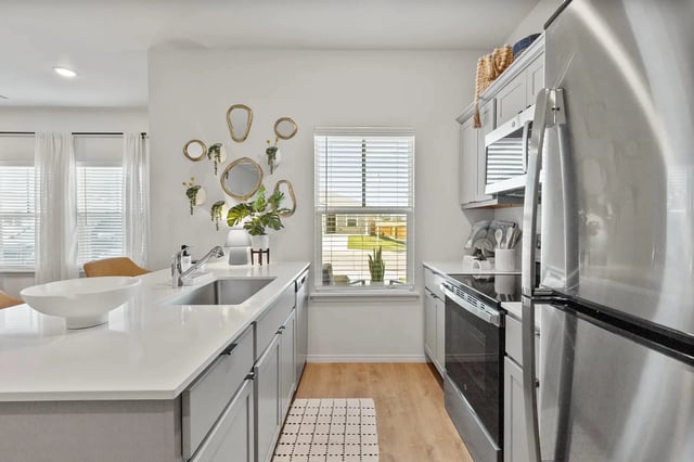 Bright kitchen with white island, stainless steel appliances, and a window.