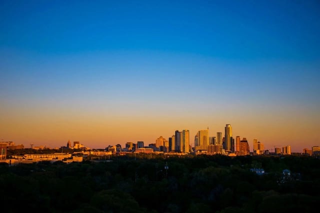 City skyline at sunset with tall buildings and a warm gradient sky.
