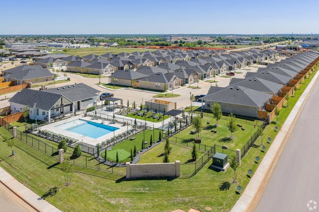 Aerial view of a residential community with a swimming pool, putting green, and townhomes.