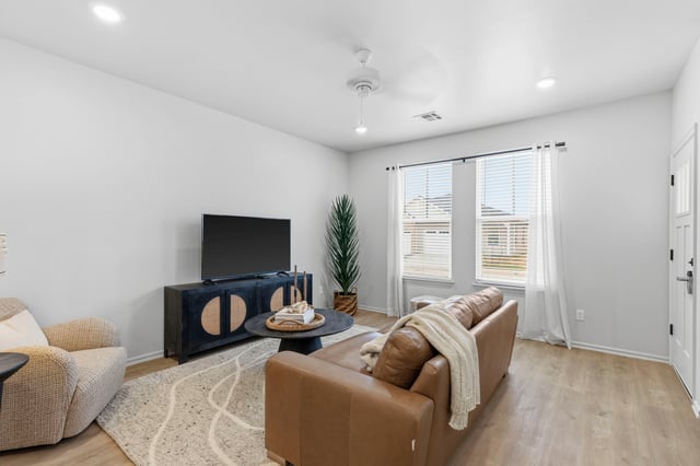 Living room with a brown sofa, armchair, coffee table, and TV.