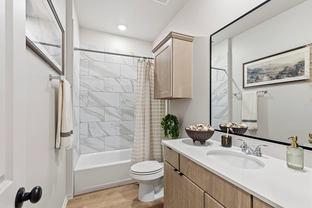 Modern bathroom with marble tile, vanity, and tub.