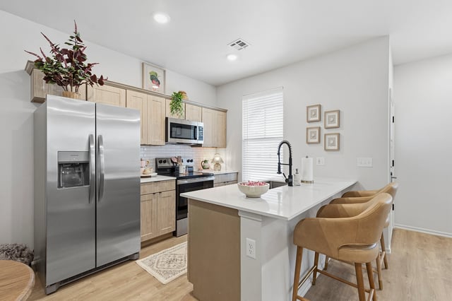 Modern kitchen with stainless steel appliances, island with bar stools, and ample cabinet space.