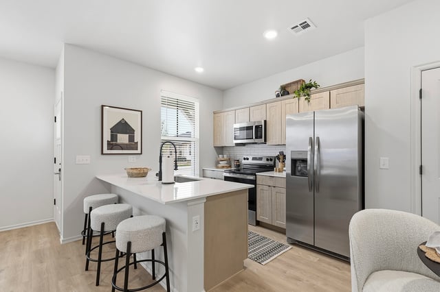 Modern kitchen with stainless steel appliances, island with bar stools, and ample cabinet space.