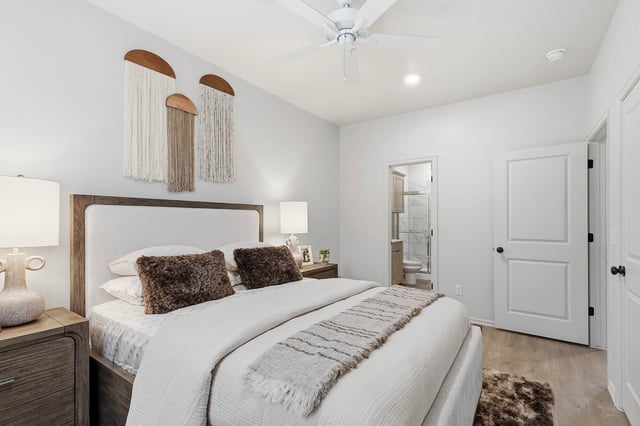 Bedroom with a king-size bed, ceiling fan, and view into a bathroom.