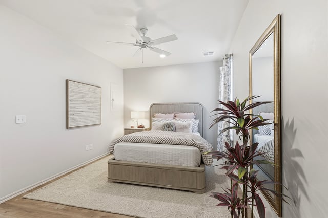 Modern bedroom with a queen-size bed, ceiling fan, and large mirror.