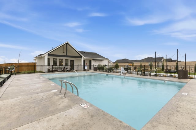 Outdoor swimming pool with lounge chairs and a clubhouse in the background.