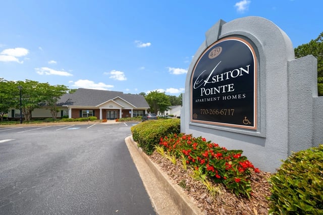 Ashton Pointe Apartment Homes monument sign with building in the background.