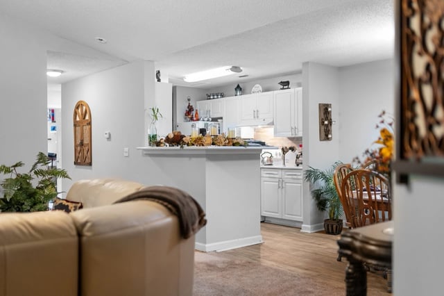 View of a kitchen and living area with a sofa and dining table.