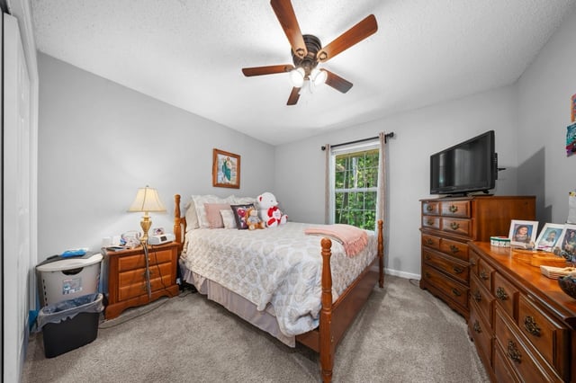 Bedroom with a queen-size bed, wooden furniture, and a ceiling fan.