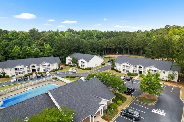 Aerial view of apartment buildings, swimming pool, and playground at Ashton Pointe apartments in Monroe, GA.