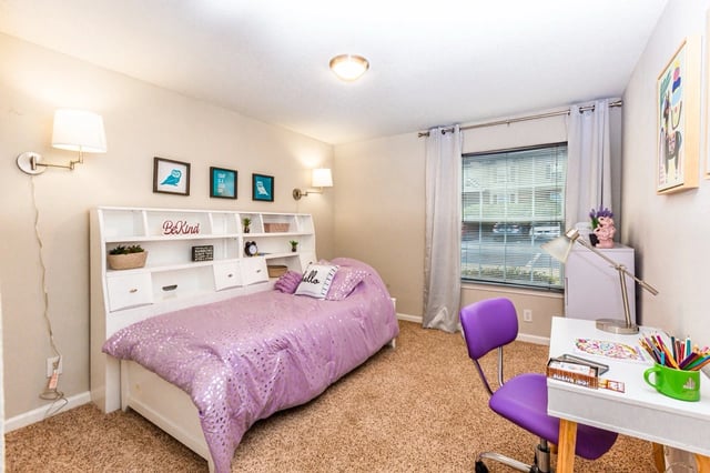 Bedroom with a purple comforter on the bed and a desk with a purple chair.