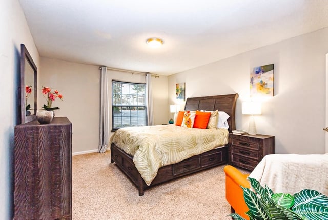 A furnished bedroom with a king-size bed, dresser, and nightstand.