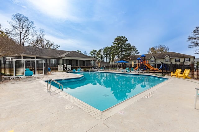 Sparkling outdoor swimming pool with lounge chairs and a playground.