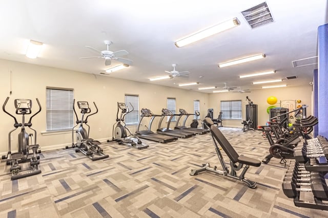 Interior of a fitness center with treadmills, ellipticals, stationary bikes, and free weights.