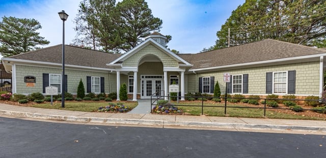 Exterior of the leasing center building with an entrance porch, landscaping, and signage.