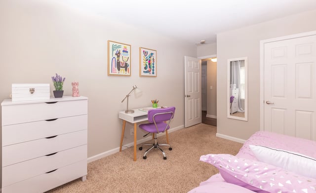 Bedroom with a desk, chair, dresser, and a bed. Browse apartments near MARTA station East Point GA—schedule your tour or call to learn more.