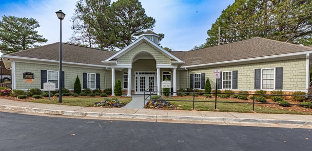 Exterior view of the leasing center with a manicured lawn and landscaping. Discover gated apartments in East Point GA—schedule a tour or call for availability details.