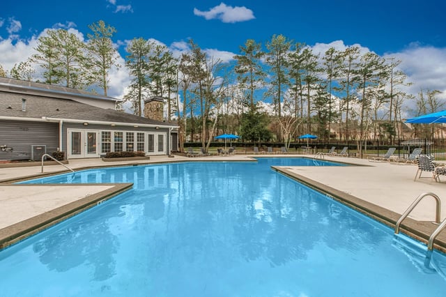 Large outdoor swimming pool with lounge chairs and umbrellas.