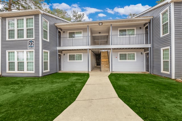 Exterior view of apartment building 22 with manicured lawns and a paved walkway.