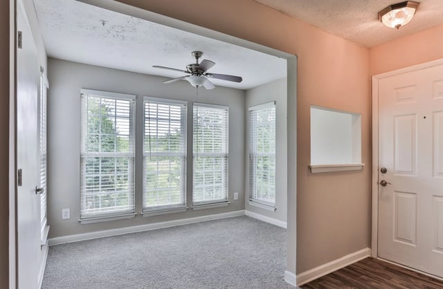 Entrance view of a living room with large windows and a ceiling fan.