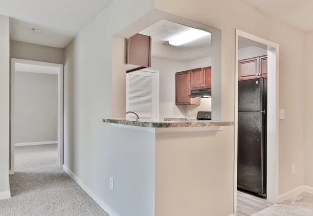 View of kitchen with dark cabinets and stainless steel appliances, pass-through bar
