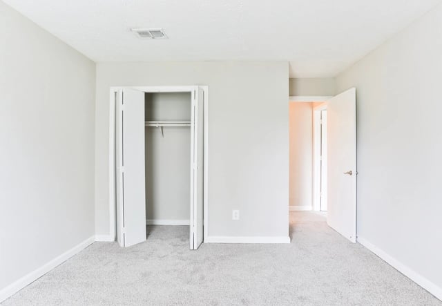 Interior view of an empty bedroom with a closet and hallway.