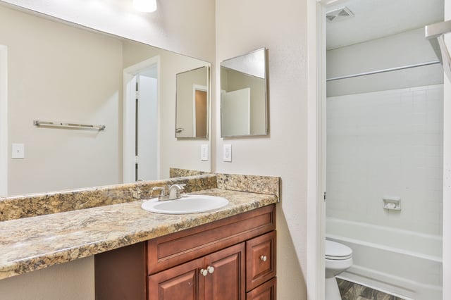 Bathroom vanity with a granite countertop, sink, and large mirror. A bathtub and toilet are visible through an open doorway.