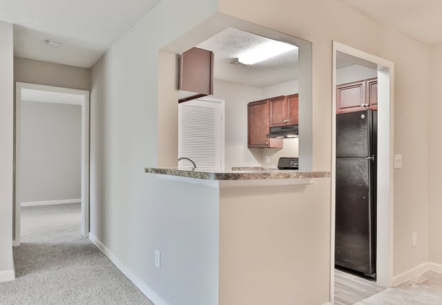 Kitchenette with breakfast bar, refrigerator, and stovetop.