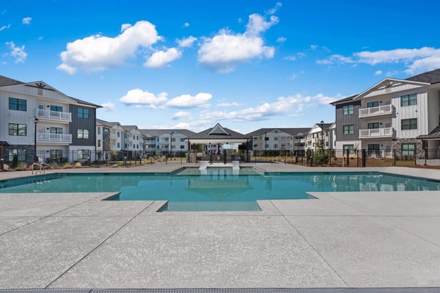 Outdoor swimming pool with lounge area and apartment buildings in the background