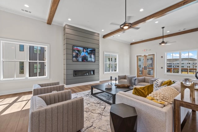 Modern lounge area with fireplace, TV, comfortable seating, and large windows.