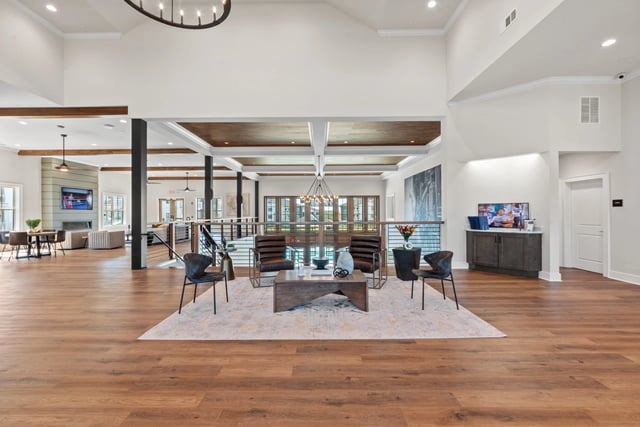 Spacious high-ceilinged common area with modern seating, a fireplace, and a television.