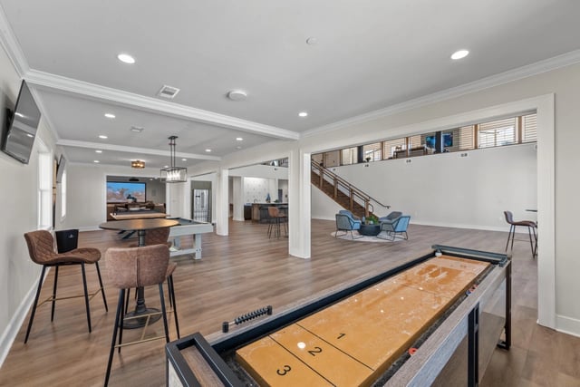 Recreation room with shuffleboard, pool table, bar, and seating.