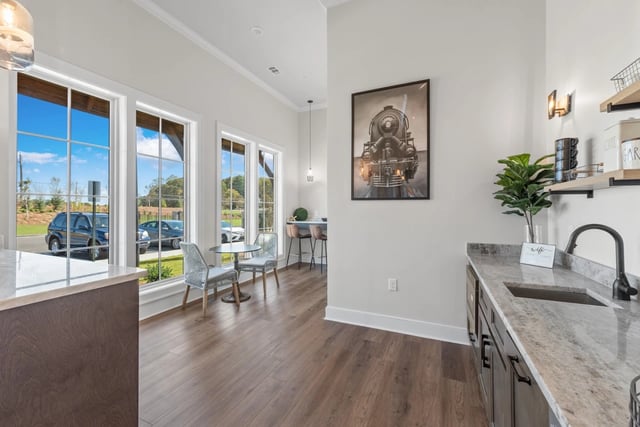 Modern community kitchen area with granite countertops, sink, and a small seating area.