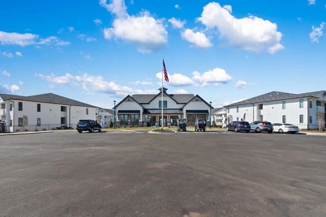 Exterior view of apartment buildings with a central clubhouse and parking lot.