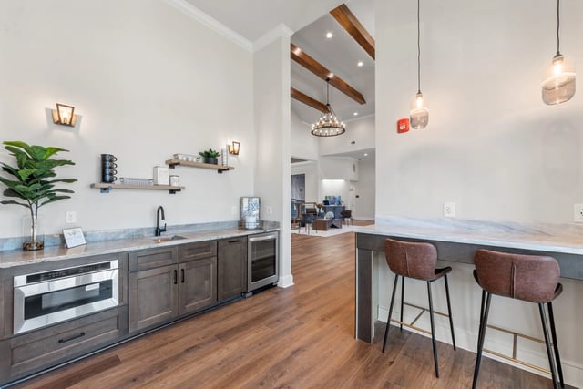 Modern wet bar with microwave, mini-fridge, and seating area.