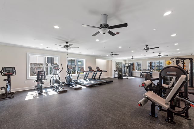 Treadmills, ellipticals, stationary bikes, and weight machines in a well-lit fitness center at The Blakely, offering apartments for rent in Pendergrass, GA.