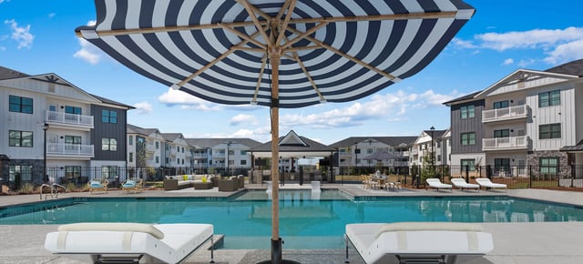Outdoor swimming pool with lounge chairs and umbrellas at an apartment complex at The Blakely, offering apartments for rent in Pendergrass, GA.
