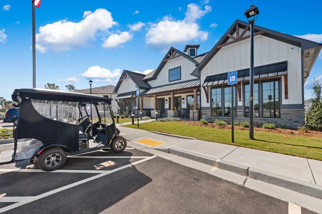 Golf cart parked in front of a modern apartment building's clubhouse with an accessible parking sign at The Blakely, offering apartments in Pendergrass, GA.