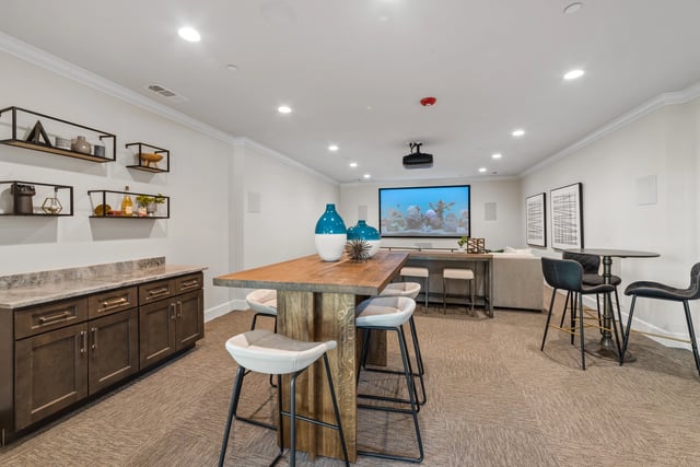 Community room with a large screen, projector, bar seating, and a counter area at The Blakely, offering apartments in Pendergrass, GA.