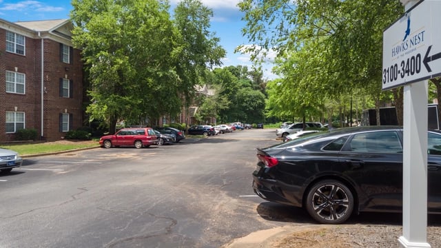Hawks Nest at The Preserve apartment building exterior with parking lot and signage.