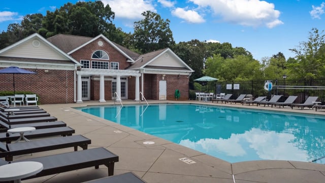 Outdoor swimming pool with lounge chairs and a brick building.