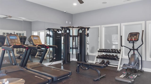 Fitness center with treadmills, elliptical, weight racks, and multi-station weight machine.