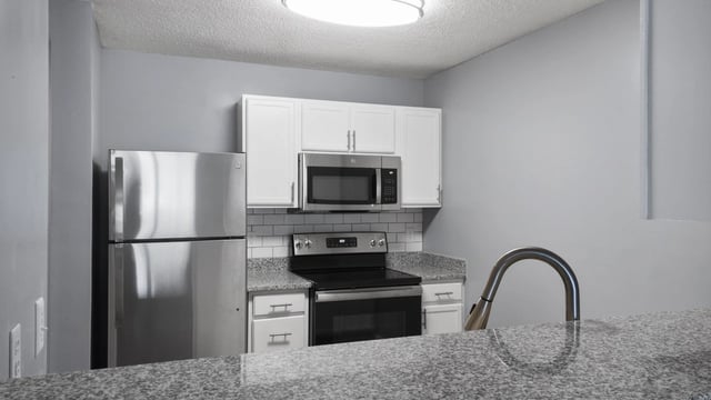 Modern kitchen with stainless steel appliances, white cabinets, and granite countertops.